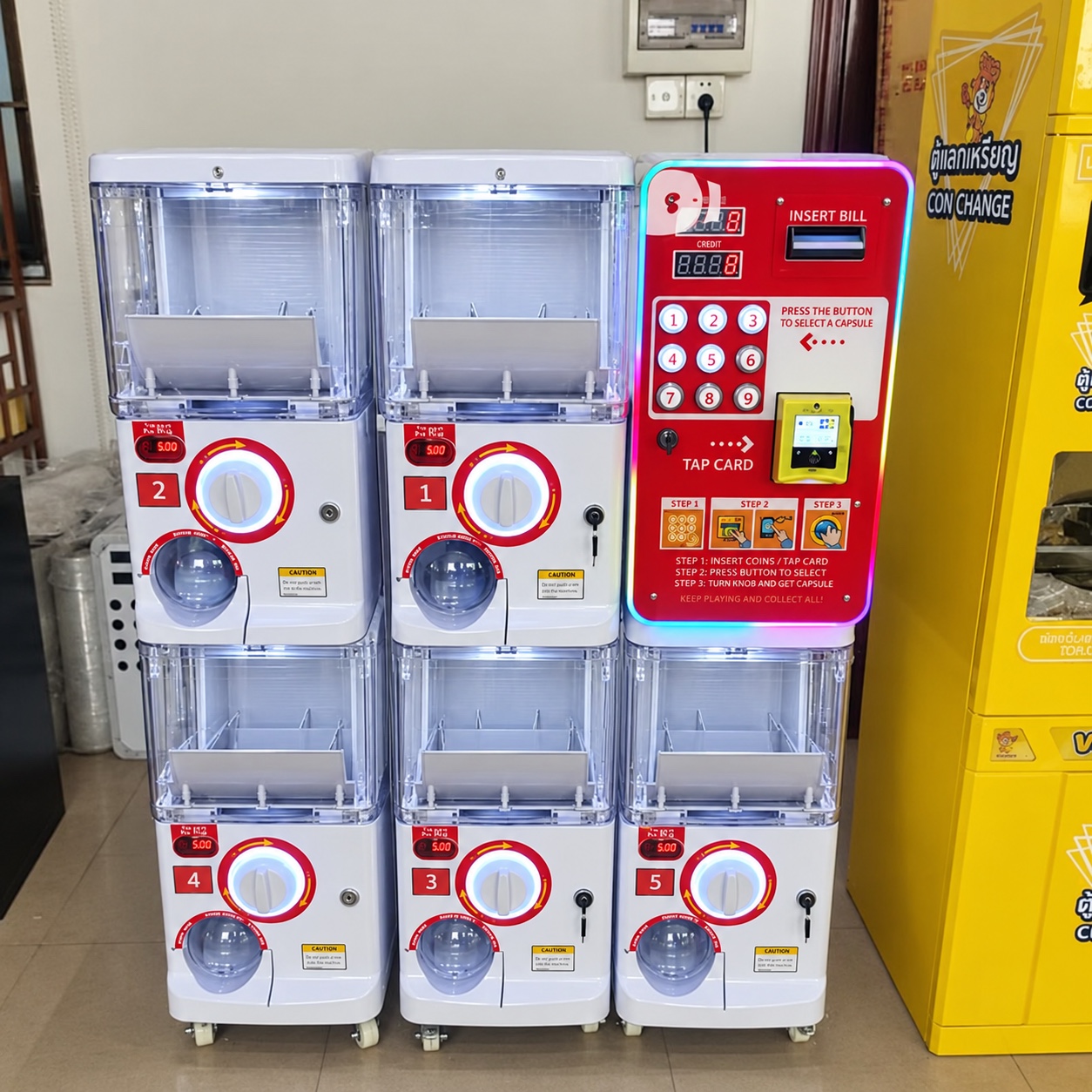 Five white capsule dispensers beside a red payment panel