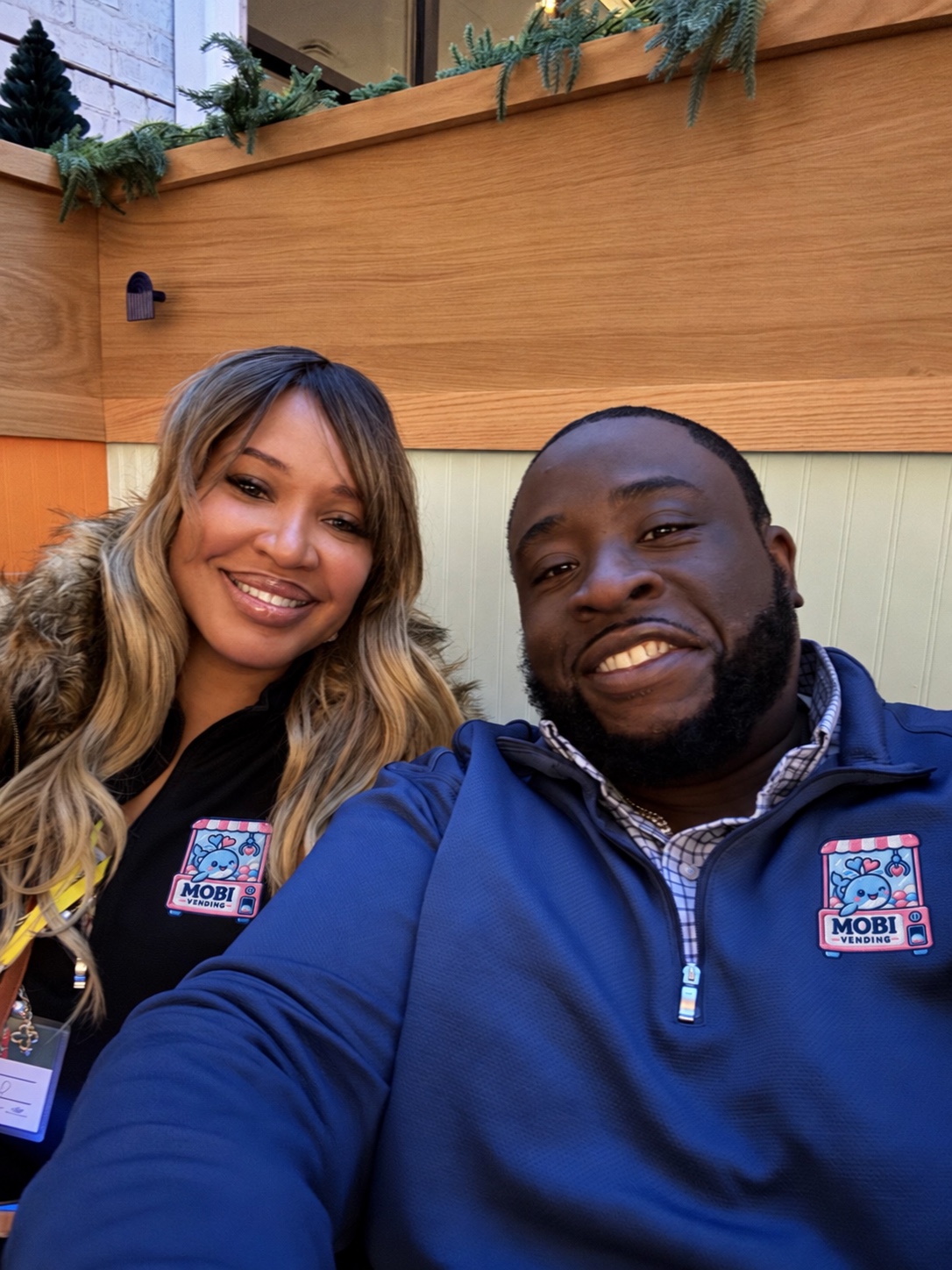 Maureen and Obi Umunna smiling together in quarter-zips with the MOBI Vending logo